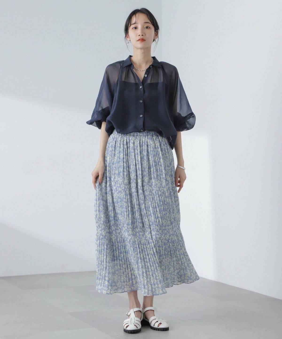 ネイビーのTシャツに柄物のプリーツスカートを合わせた女性