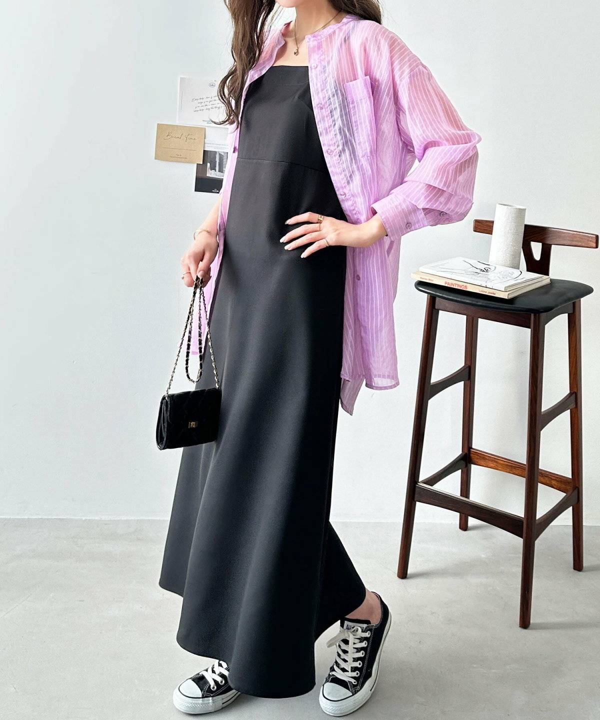 ブラックコーデのピンクのシャツを羽織った女性