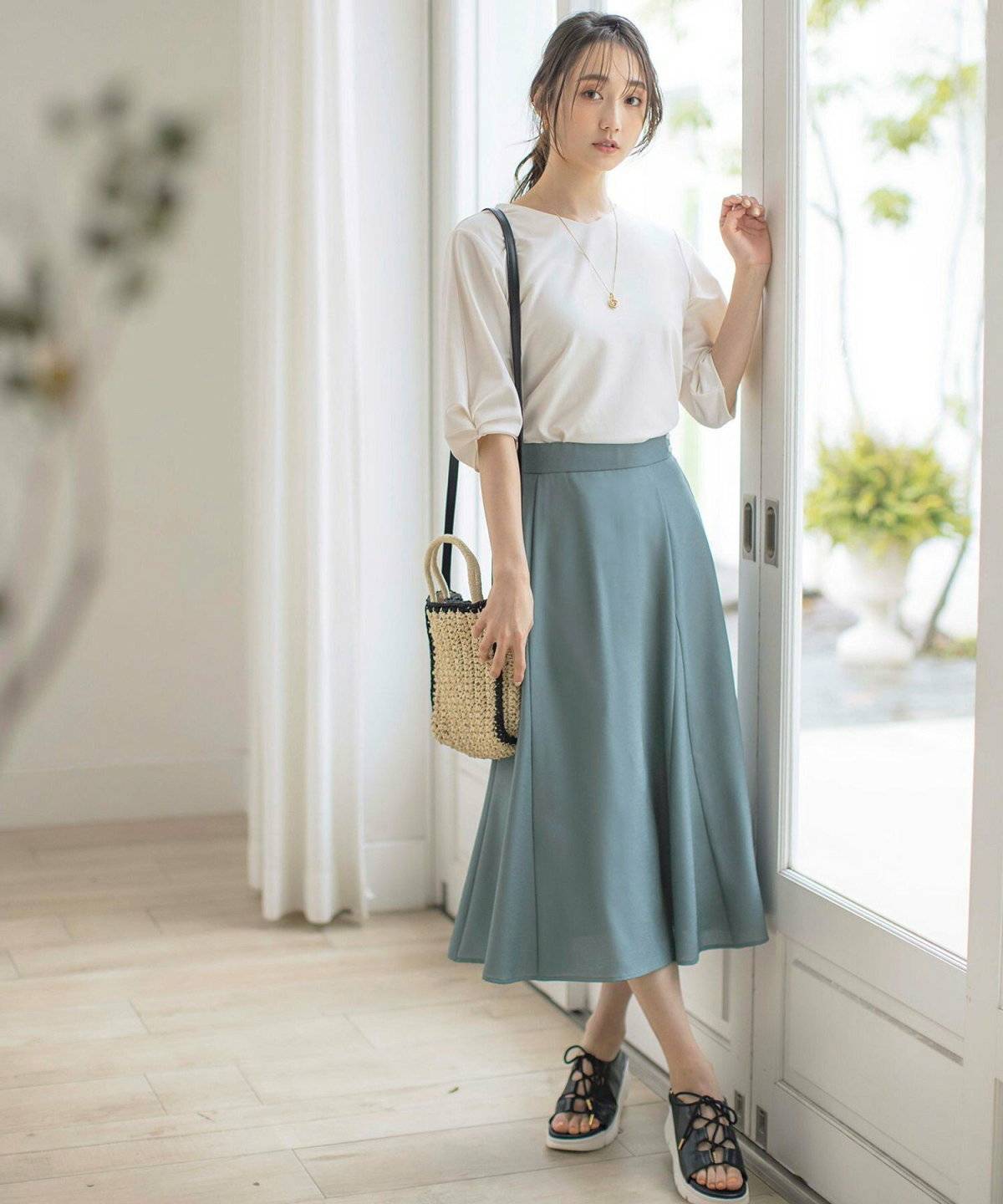 黒のロゴTシャツにグリーンのスカートを合わせた女性