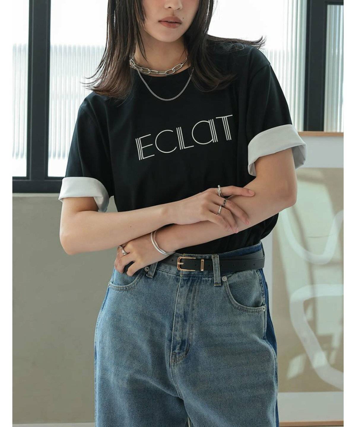 黒のロゴTシャツにデニムを合わせた女性