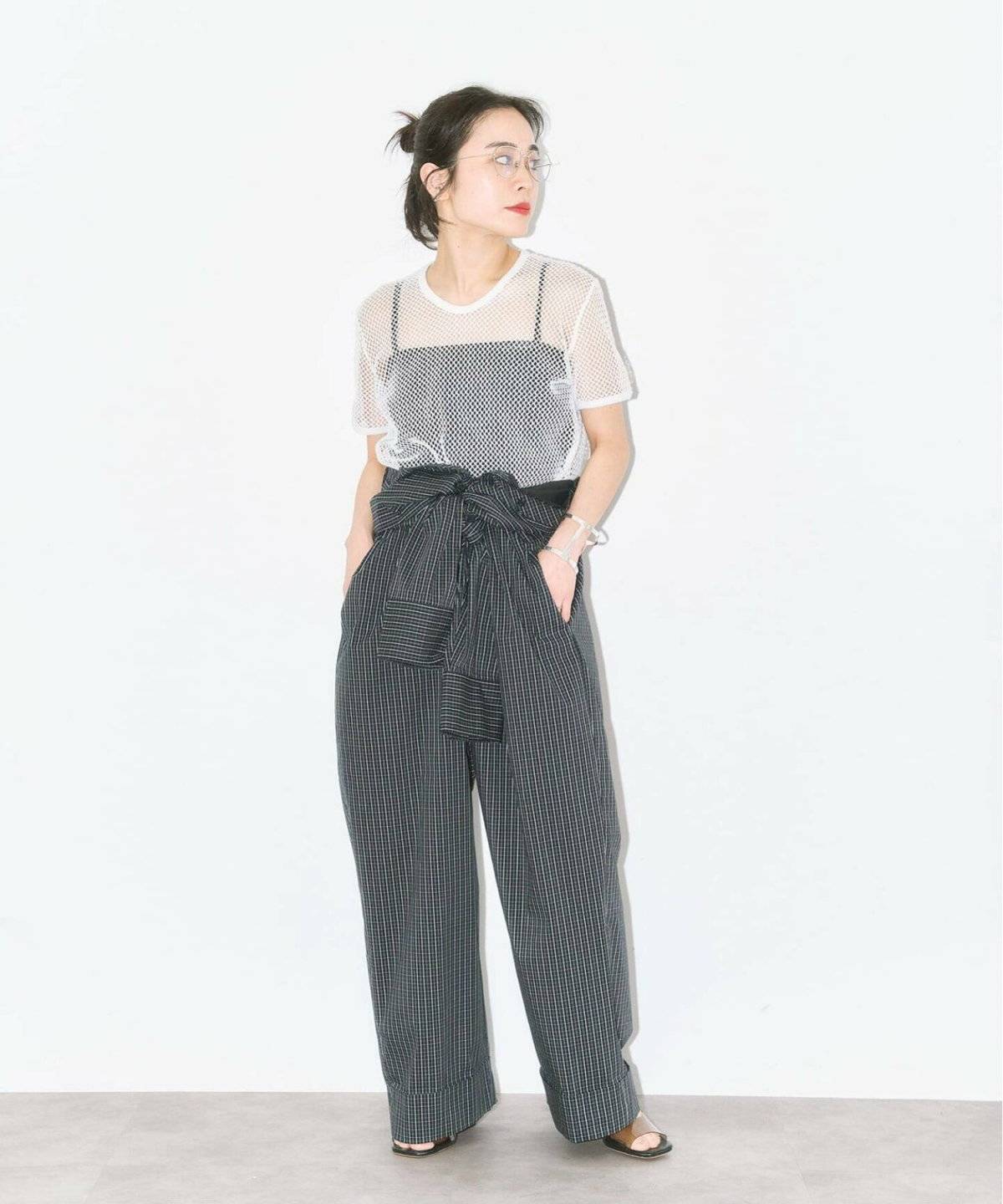 黒トップスに黒の柄パンツを合わせた女性