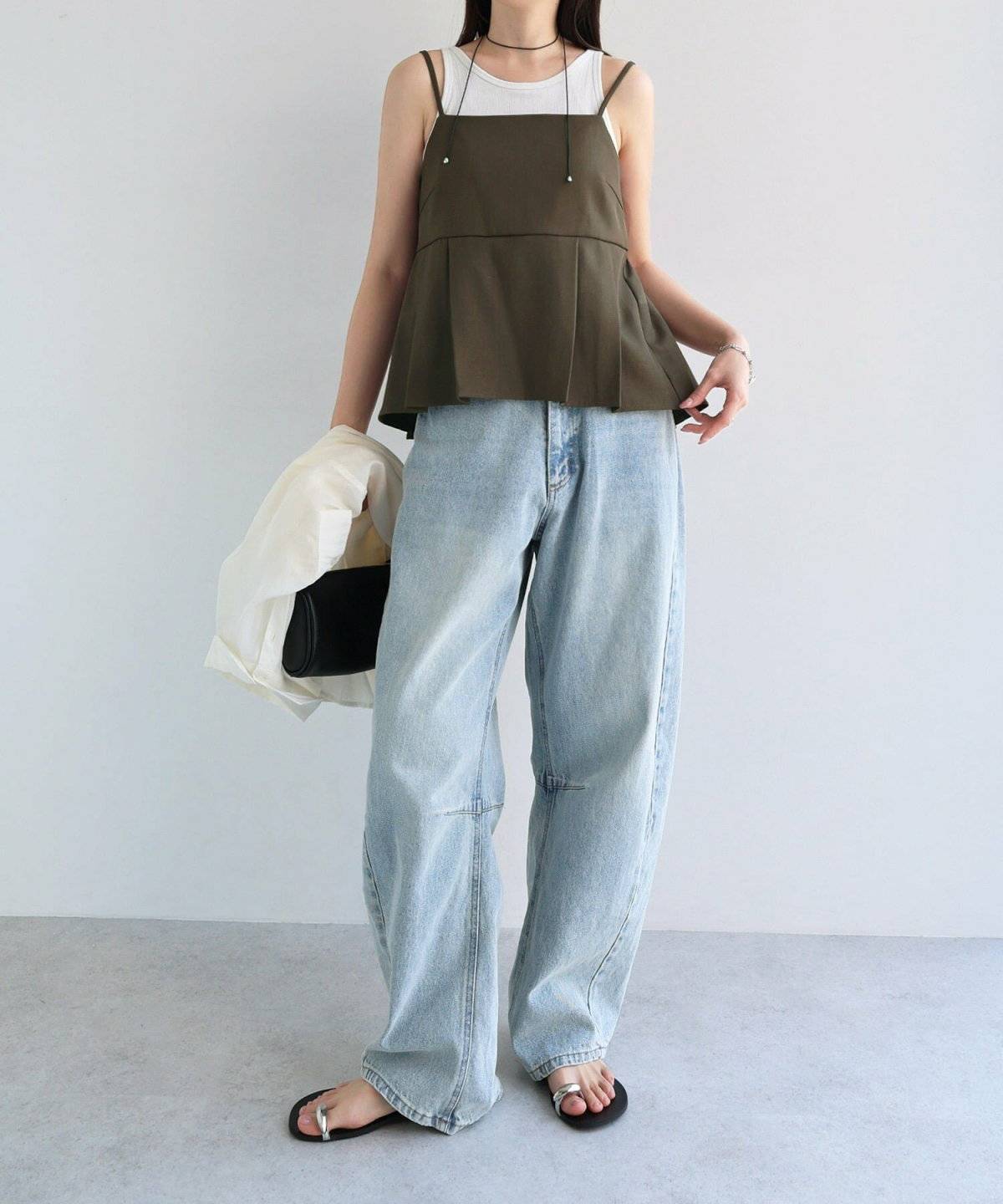 ノースリーブのTシャツにデニムを合わせてキャミソールを重ねた女性