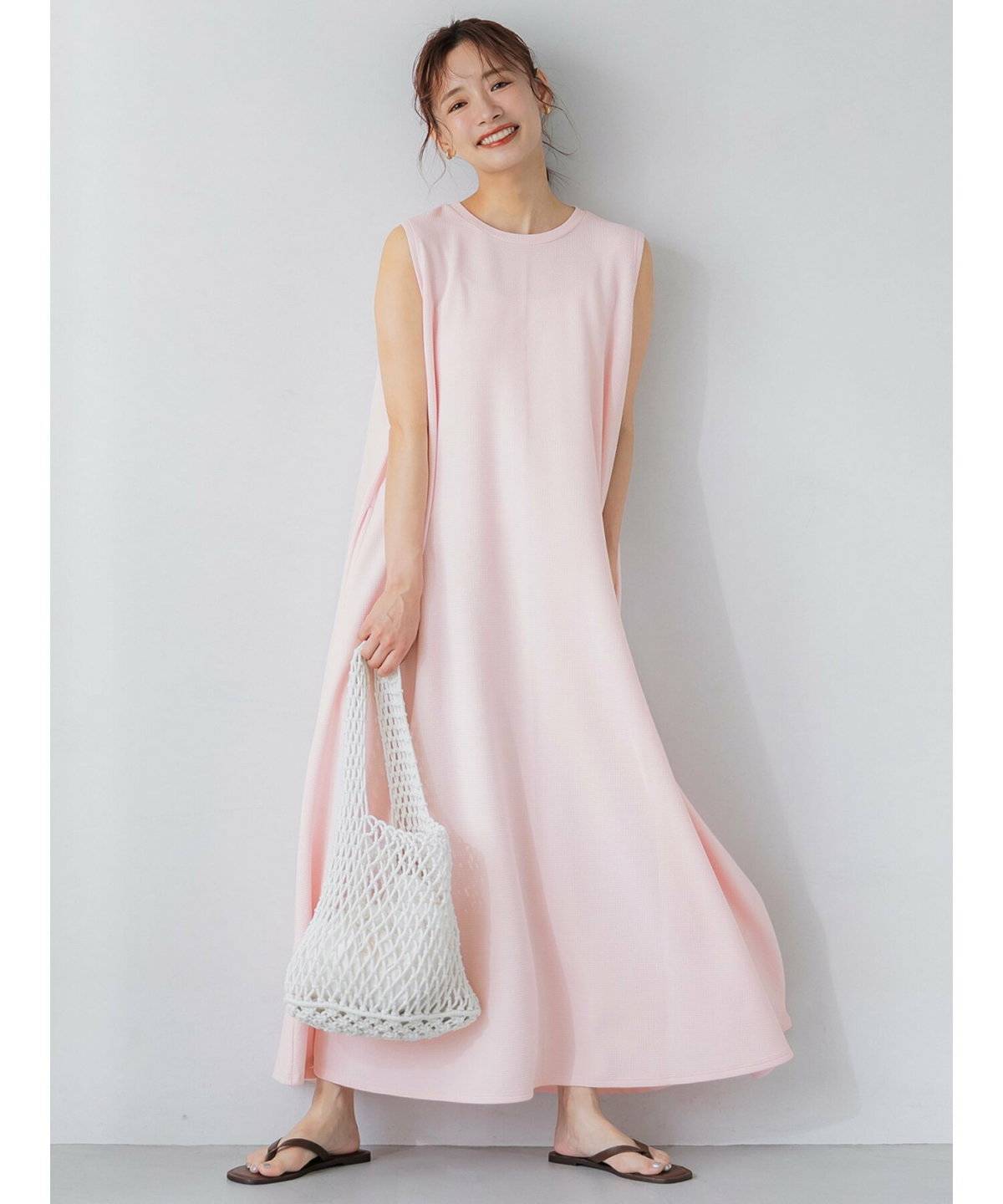 パープルのワンピースにボーダー柄のトップスを肩掛けした女性