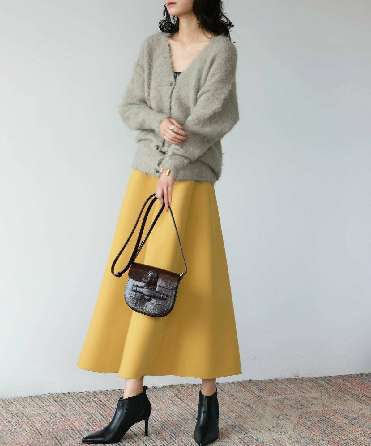 ブラウンのカーディガンにイエローのスカートを合わせた女性