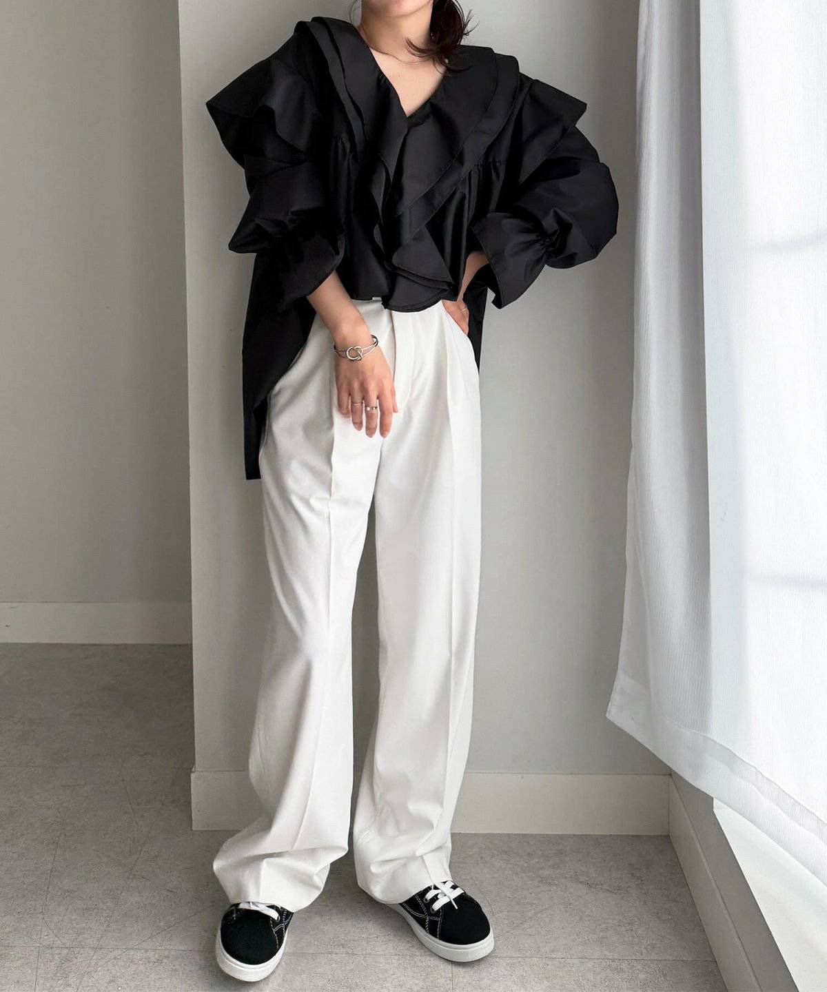 黒ブラウスにカーキのパンツを合わせた女性