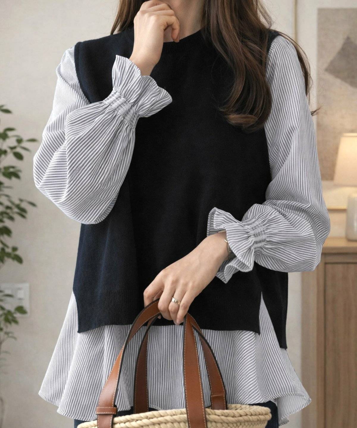 ストライプ柄シャツにニットベストを重ねてリブパンツを合わせた女性