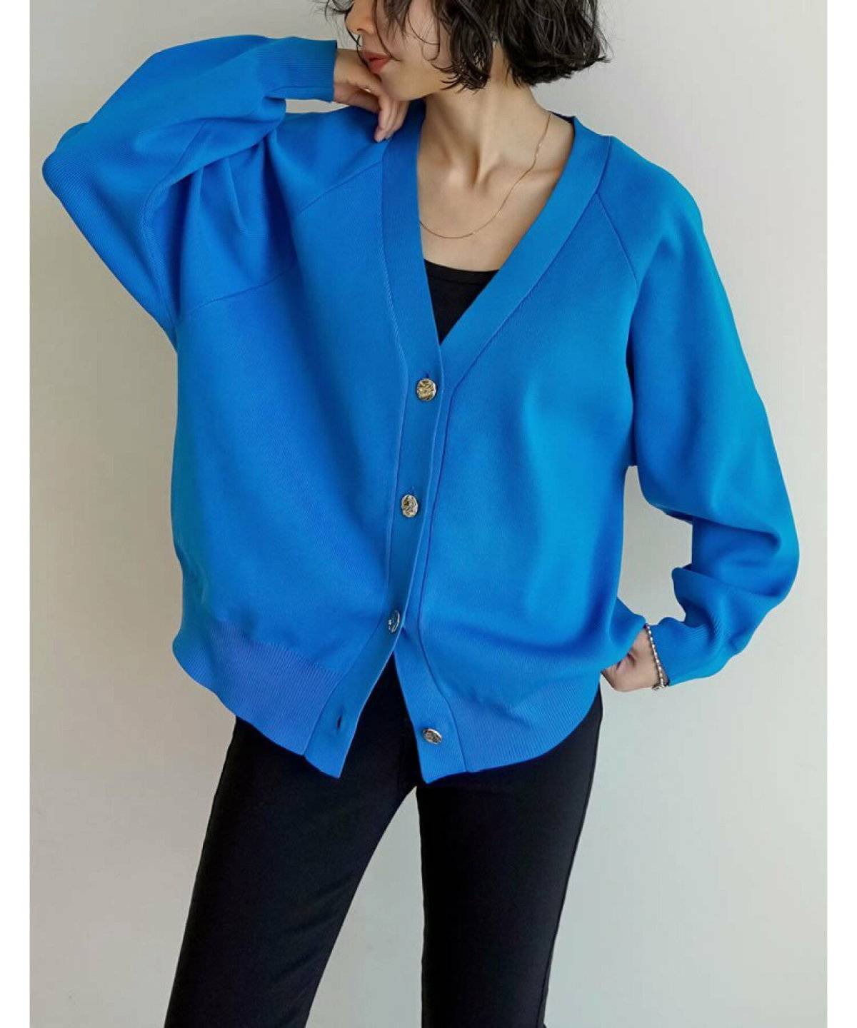 ブルーのカーディガンに黒デニムを合わせた女性