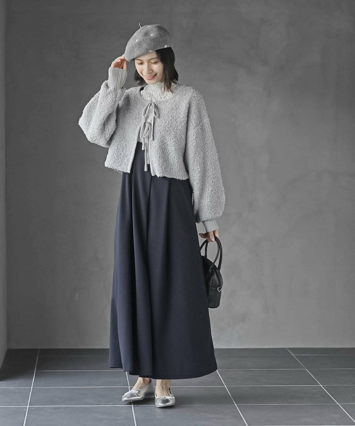 グレーのワンピースに黒の中綿ベストを重ねた女性