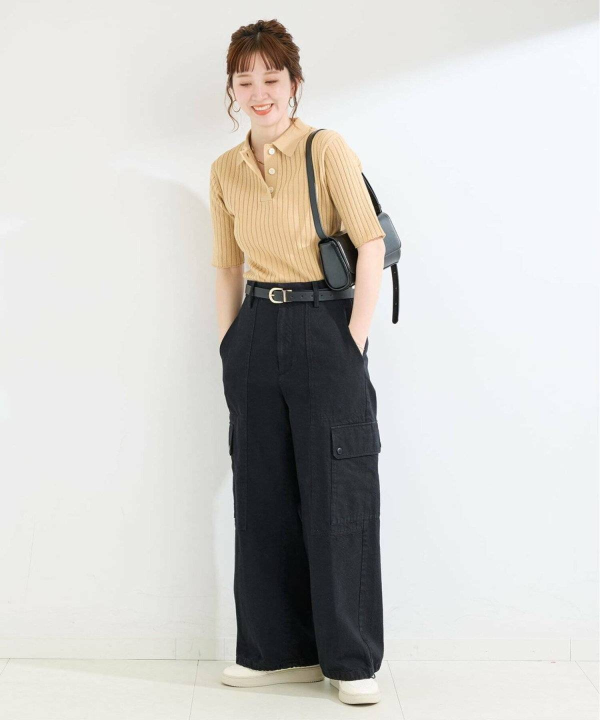 ベージュニットに黒のカーゴパンツを合わせた女性