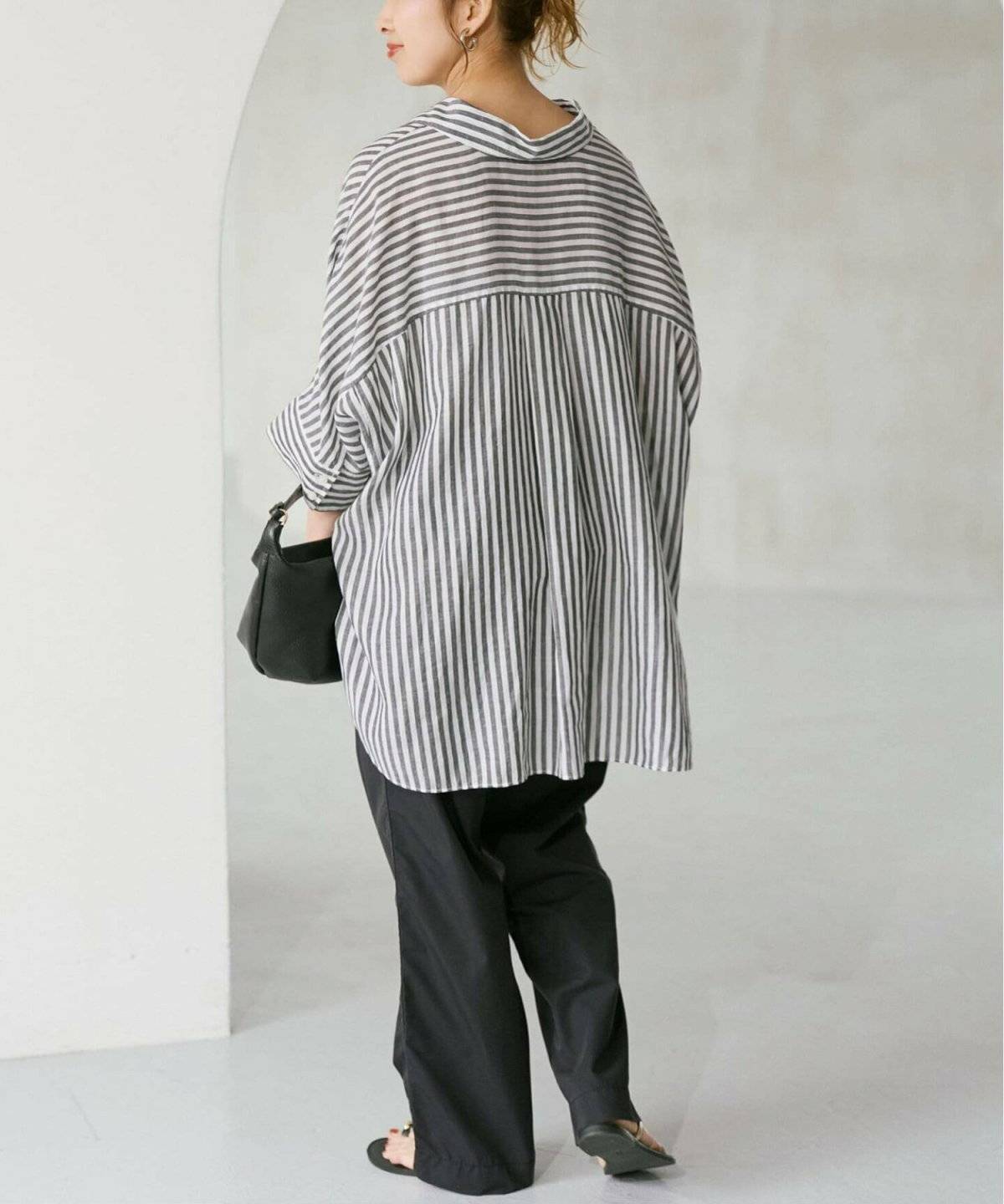 Tシャツとカーゴパンツを合わせてストライプ柄のシャツワンピースを羽織った女性