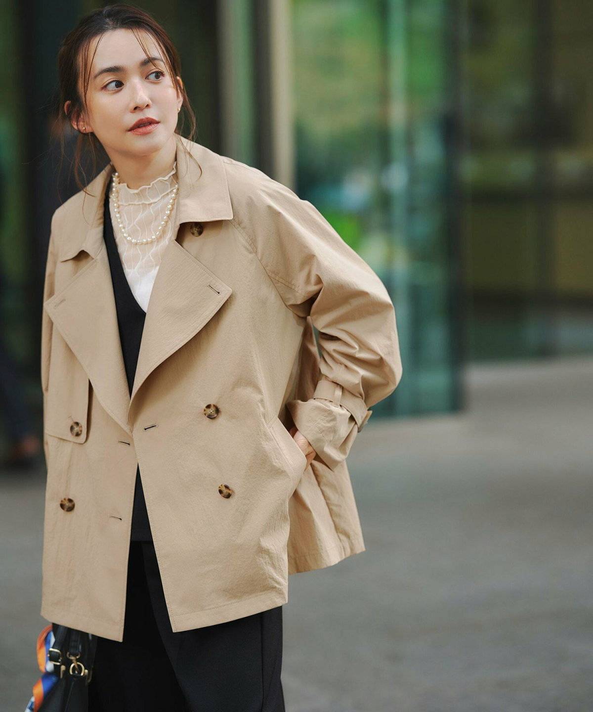 ブラックコーデにベージュのアウターを羽織った女性