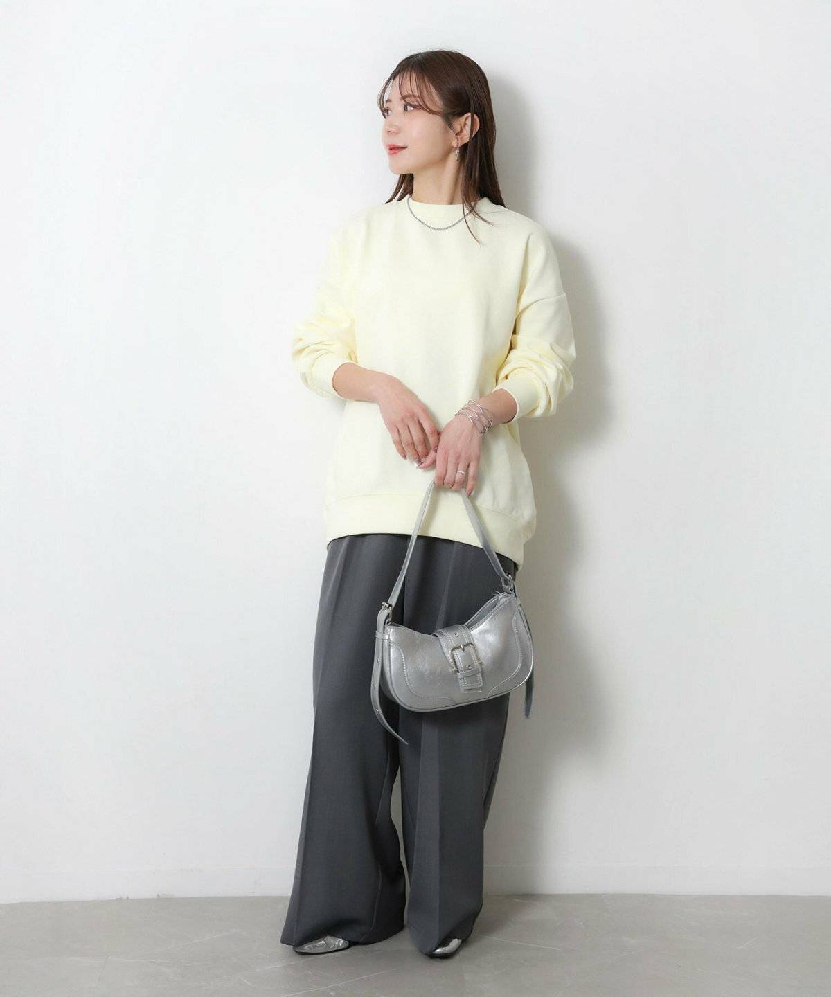 イエローのスウェットにグレーのパンツを合わせた女性