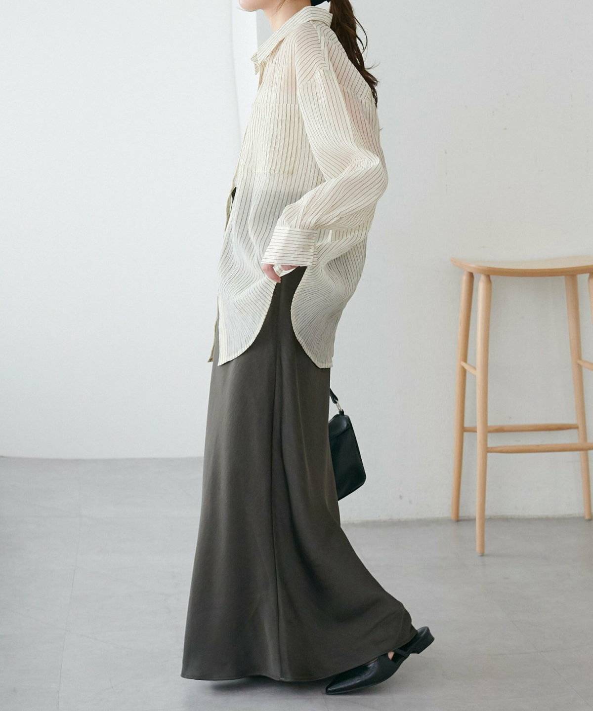 ストライプ柄シャツに黒スカートを合わせた女性