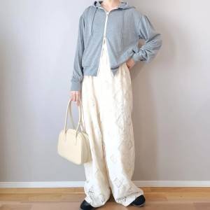  グレーのパーカーに白パンツを合わせた女性 