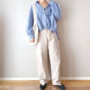  ブルーのシャツに白パンツを合わせた女性 
