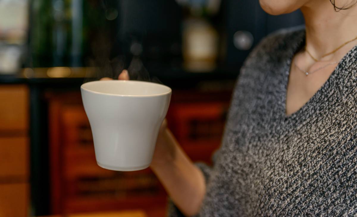 温かい飲み物を飲む女性の手元