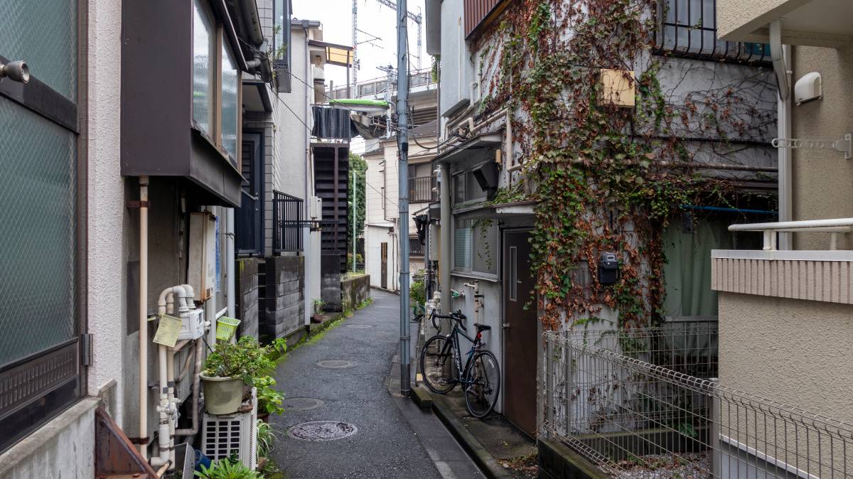 住宅に挟まれた、細く曲がる路地裏の風景