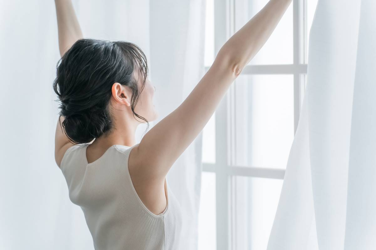 起きてカーテンを開ける女性