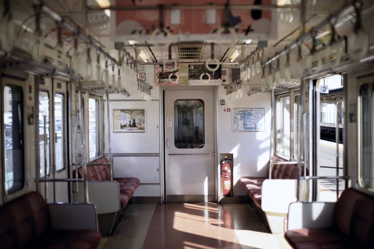 昼の光が差し込む、座席の空いた電車の車内