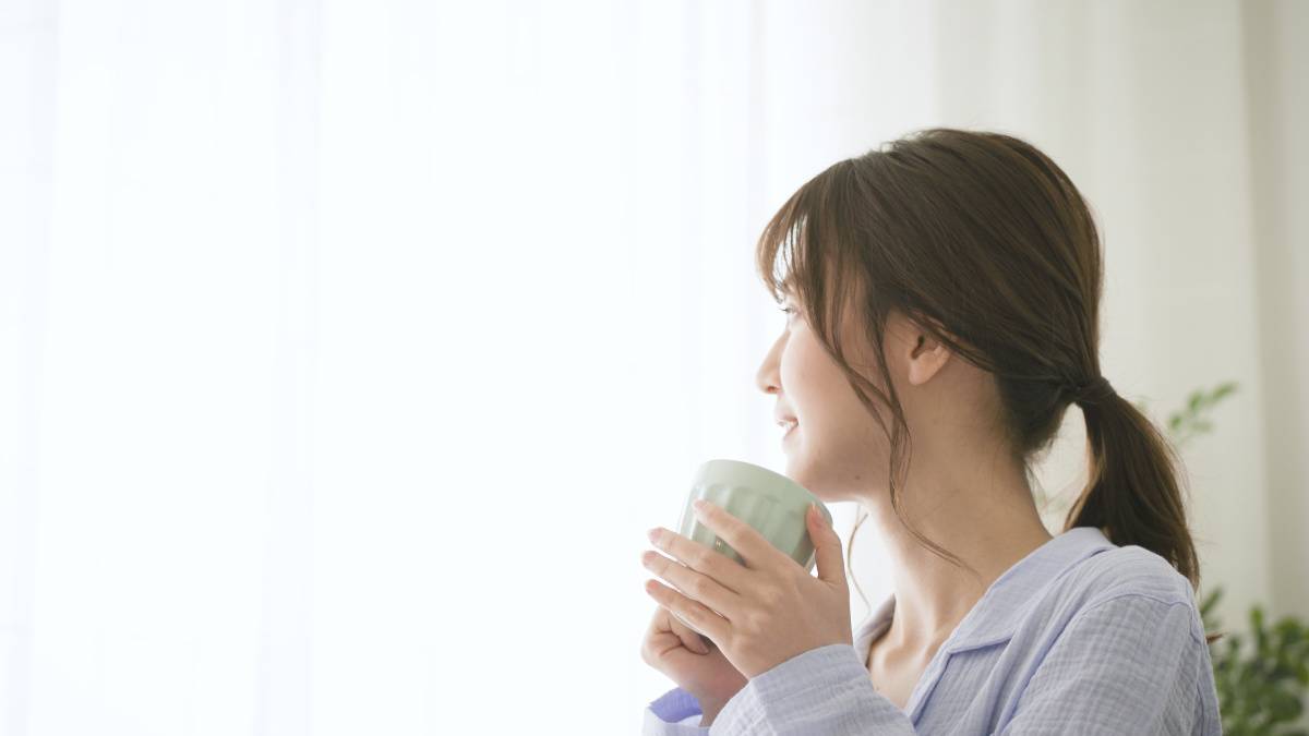 マグカップで飲み物を飲む女性