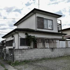  住宅街に建つ、二階の窓が見える古い一軒家の外観 