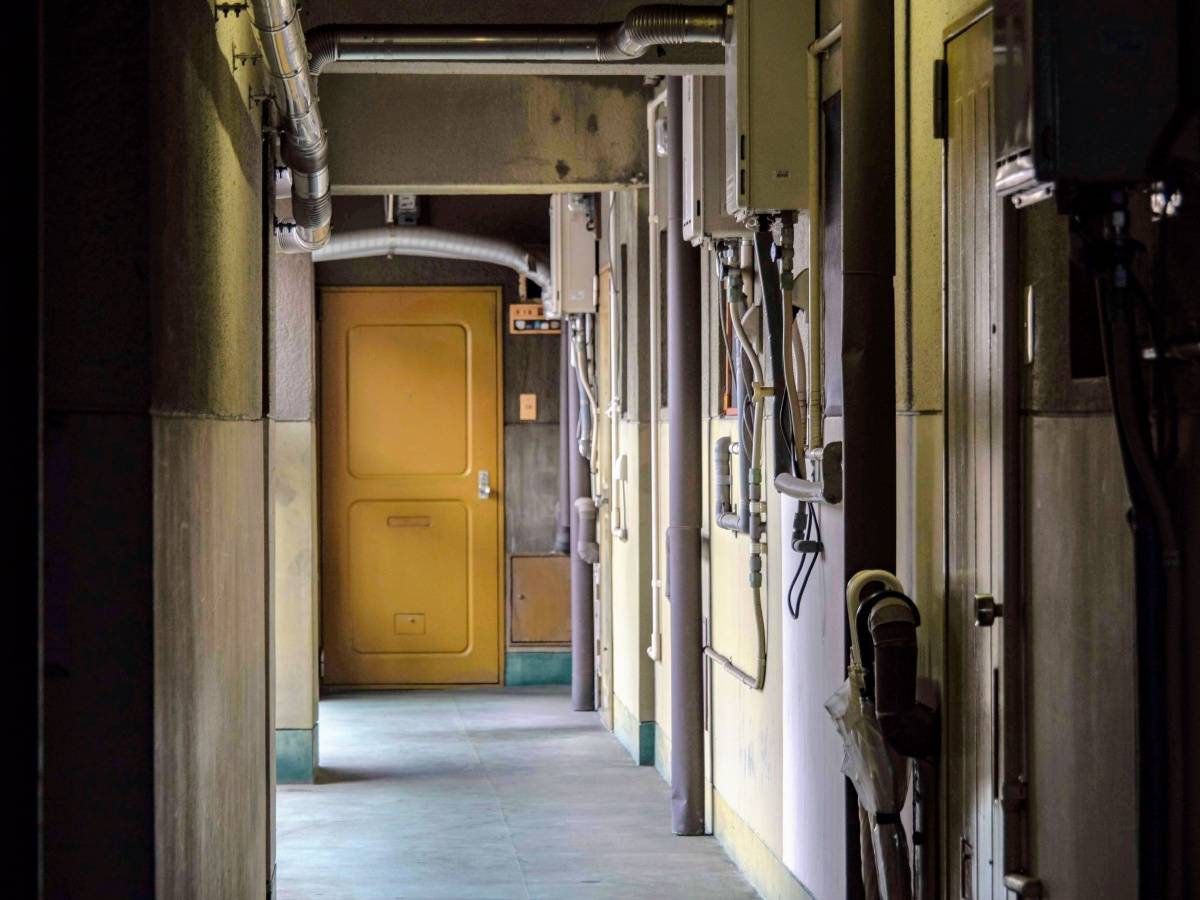 部屋の扉が並ぶ薄暗い通路。奥に黄色の扉