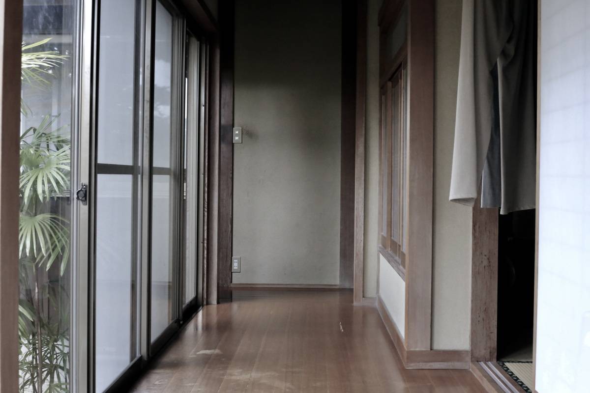 薄暗い古い廊下。外の景色と部屋の内装が見えている。