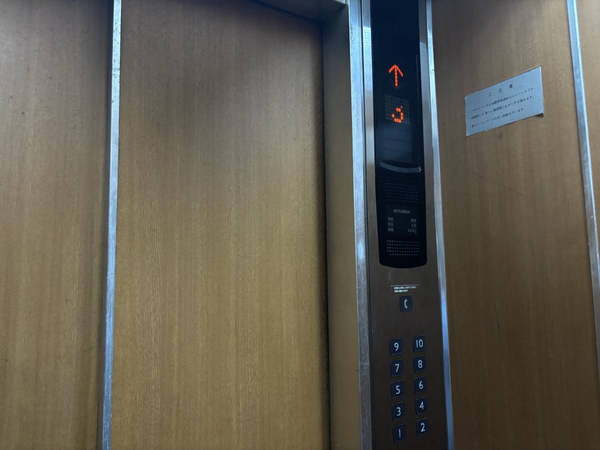 古いエレベーターの内部。階数表示と1階から10階までのボタンが並んでいる。